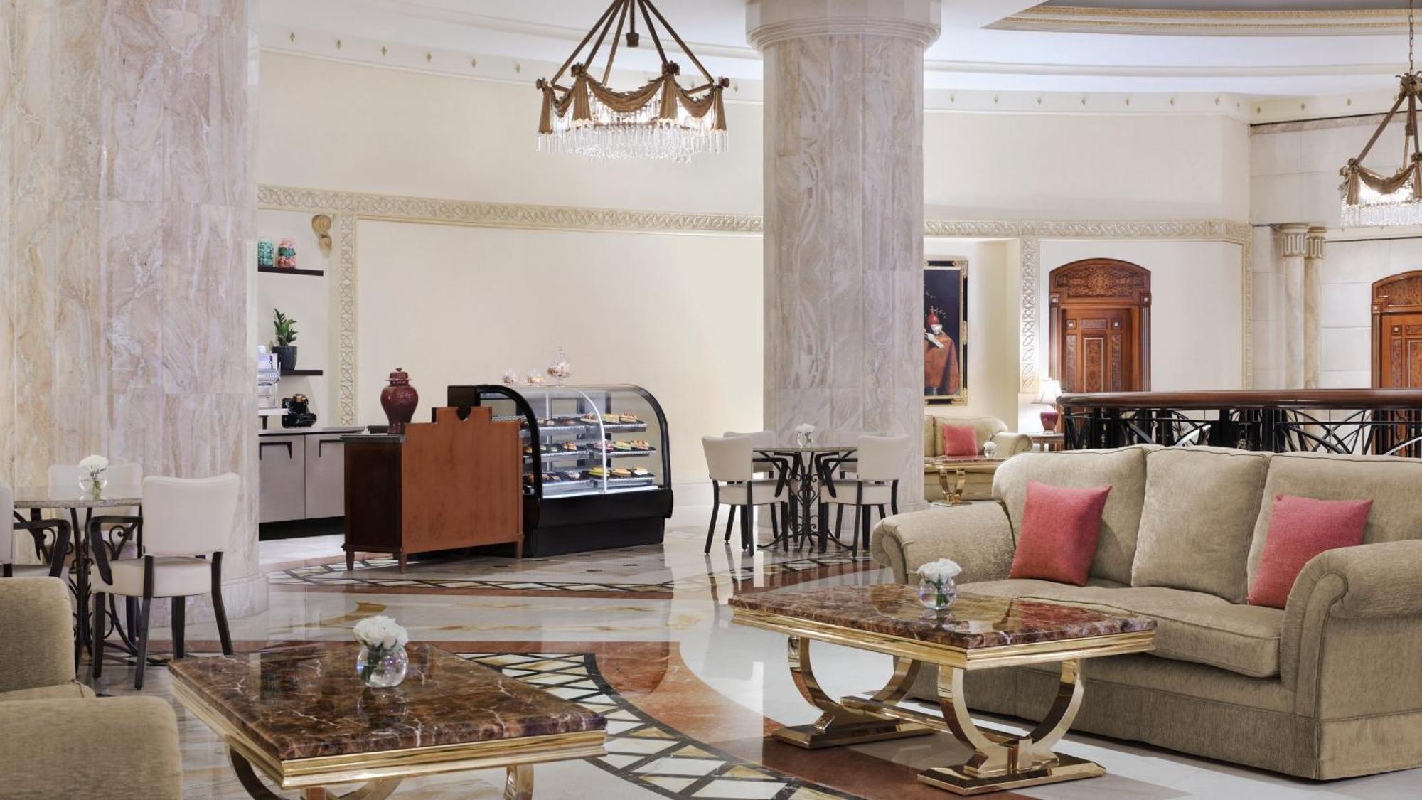 Intercontinental Dar Al Iman Madinah By Ihg Hotel Medina Exterior foto The photo shows a luxurious hotel lobby or lounge area. It features elegant marble floors and tall columns. There are comfortable seating arrangements with a sofa and stylish tables that have marble tops. A display case for pastries or refreshments i