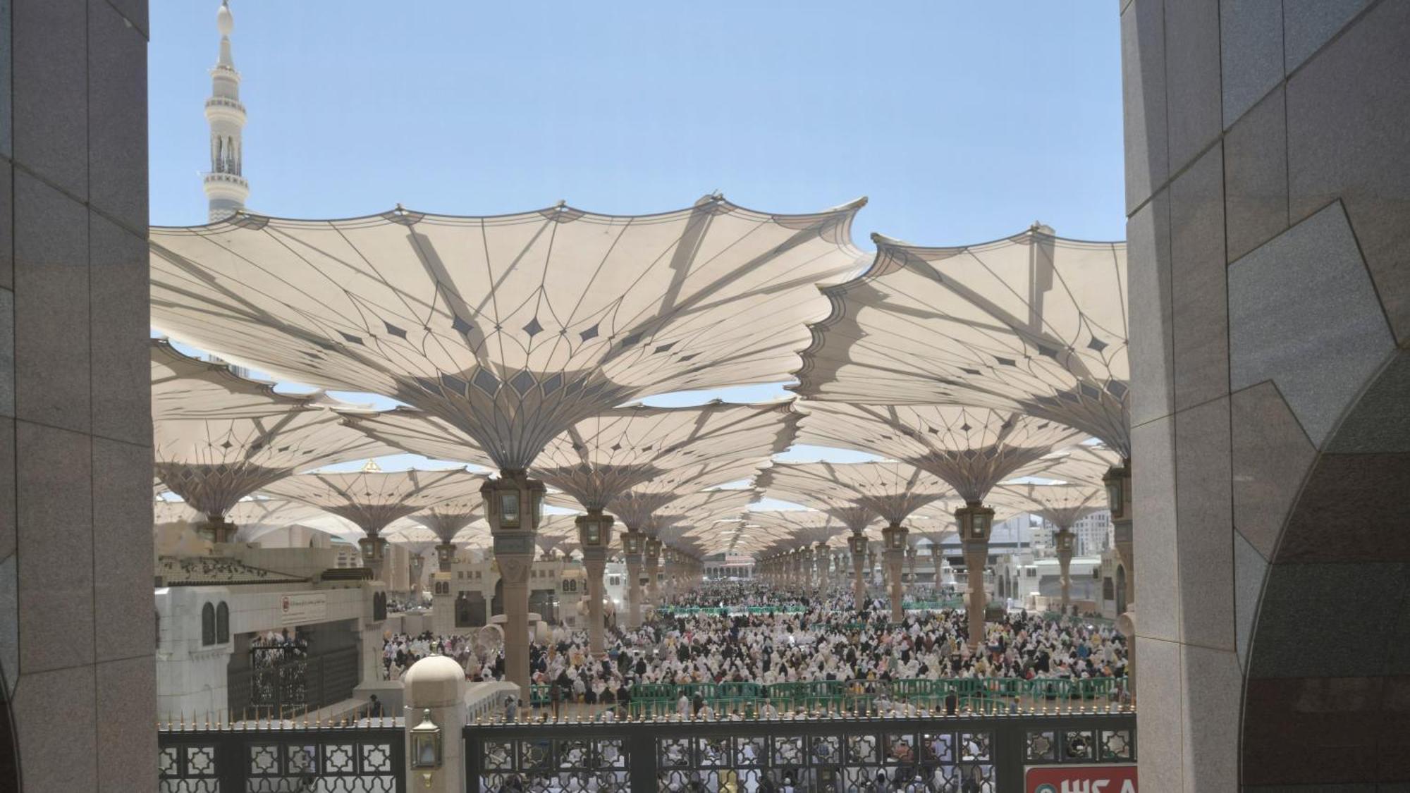 Intercontinental Dar Al Iman Madinah By Ihg Hotel Medina Exterior foto The photo shows a large open area covered by expansive canopies, likely designed to provide shade for the people below. Underneath the canopies, there are many individuals gathered, possibly participating in a religious event or gathering. In the bac