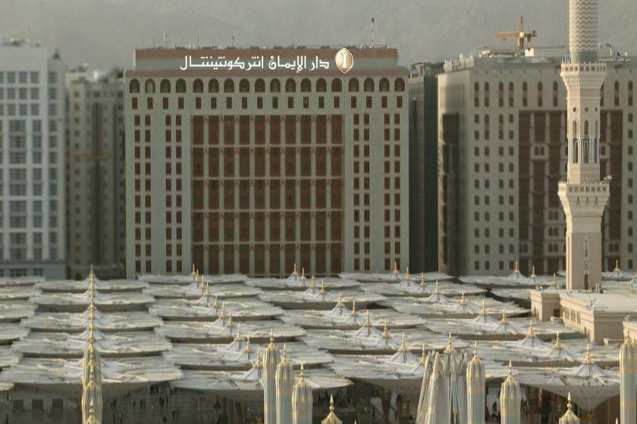 Intercontinental Dar Al Iman Madinah By Ihg Hotel Medina Exterior foto The photo shows a view of a large building with a modern architectural design, which appears to be a hotel or a commercial establishment. In front of the building, there are several large white canopies that provide shade, likely in a public space or